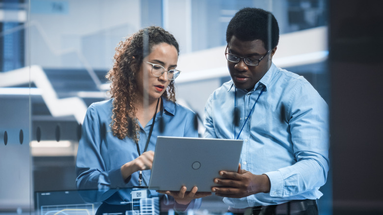 Two professionals look at a laptop