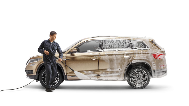 A professional detailer, detailing a car with a power sprayer