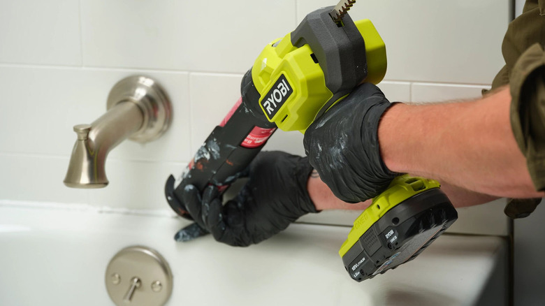 person using ryobi caulking gun