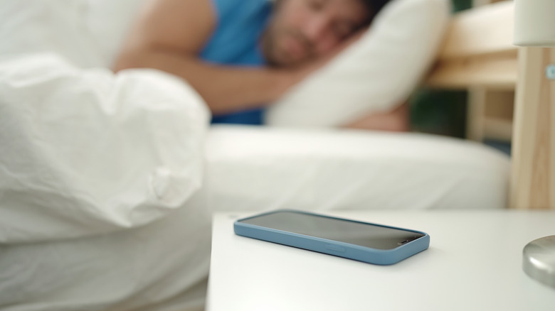 Man sleeping phone bedside table