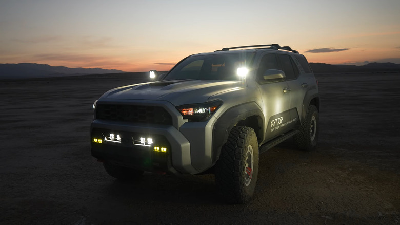 A sixth-gen Toyota 4Runner with off-road lights at dusk.