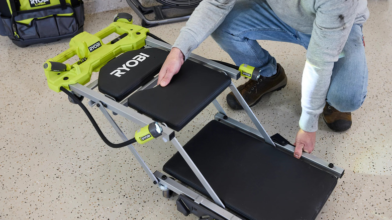 A person unfolding the Ryobi creeper/seat