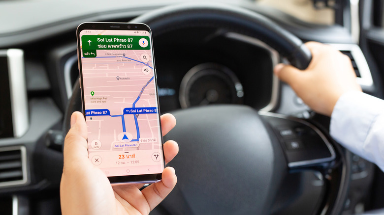 Person in car using Google Maps smartphone