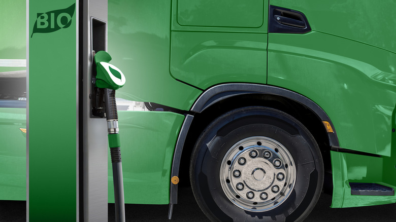 A green semi truck parked at a fuel stop, with the word "bio" printed onto the fuel pump housing.