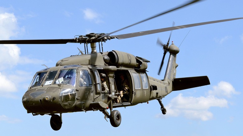 A UH-60 Black Hawk flying over blue, cloudy skies