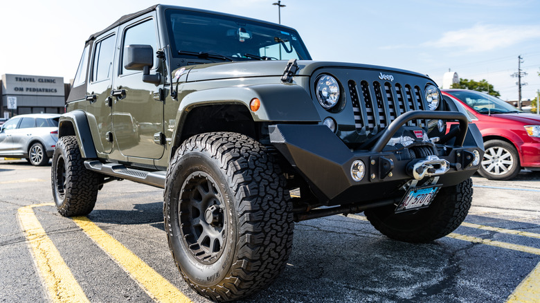 Front 3/4 view of modified Jeep Wrangler parked in parking lot.