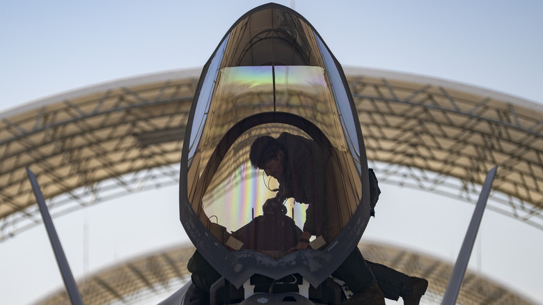 Pilot climbing into a fighter jet cockpit