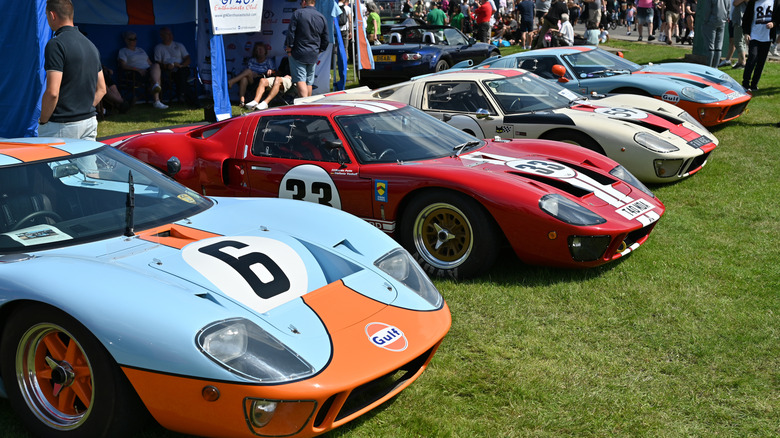 Lineup of Ford GT40 MkIIIs at a car show, right-side view of four examples in racing liveries