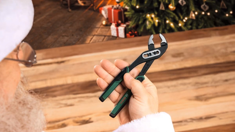 Santa Claus looking at a Bosch hand tool (pliers) from the advent calendar