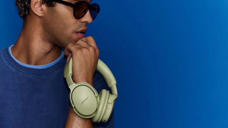 A man holding a green pair of Bose QuietComfort 2nd Gen headphones.