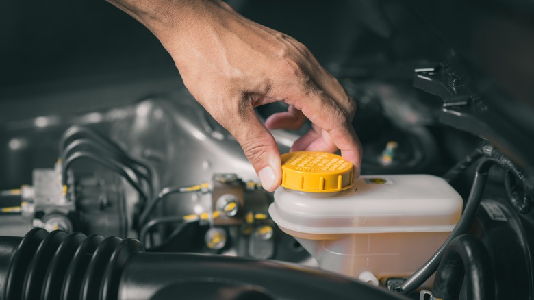 Driver checking brake fluid