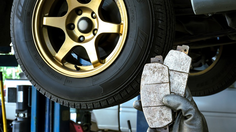 A man holding break pads in a garage