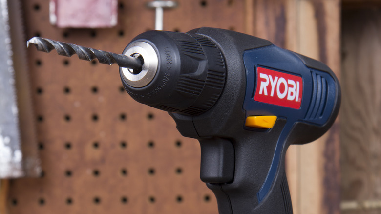 A RYOBI drill stands on surface