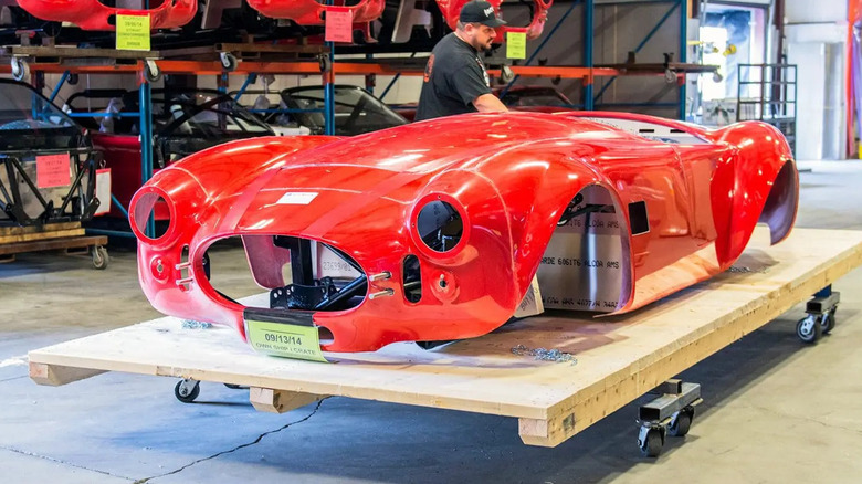 red Factory Five Mk4 kit car shell on wooden platform in shop