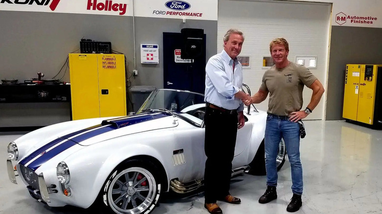two men in garage shaking hands in front of Shelby Cobra kit car