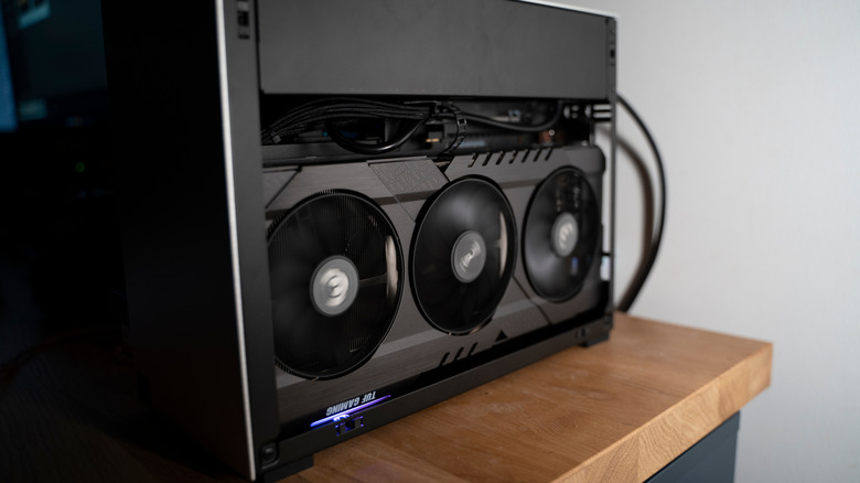A small form factor PC with the case open, showing a big Asus TUF GPU