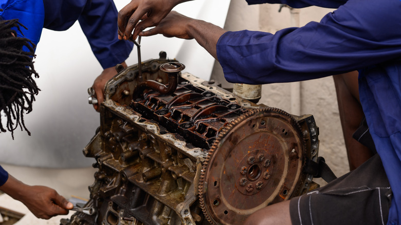 two mechanics dismantling a rusty engine