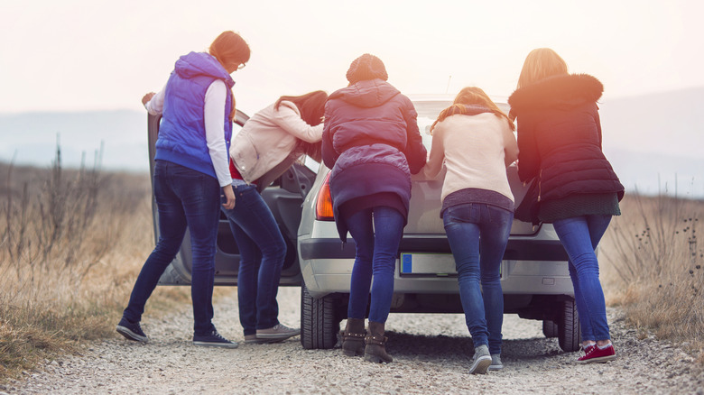 Group of people pushing a car