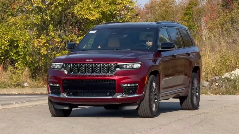 A person driving a red 2025 Jeep Grand Cherokee L.