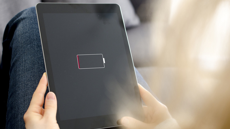 A women holding a tablet with low battery warning icon