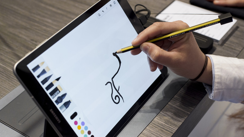 A person drawing on a white tablet