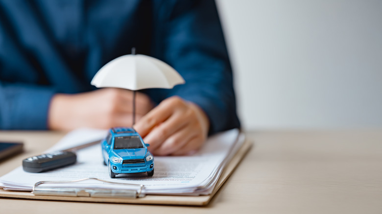 salesperson holding umbrella over car figurine