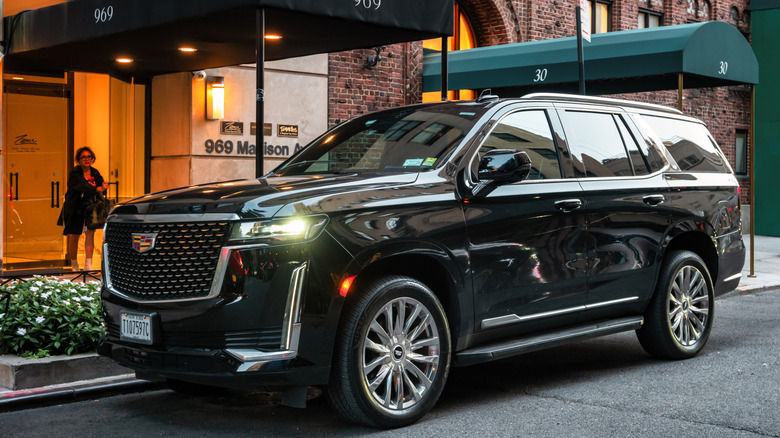 A black Cadillac Escalade parked in front of a building.