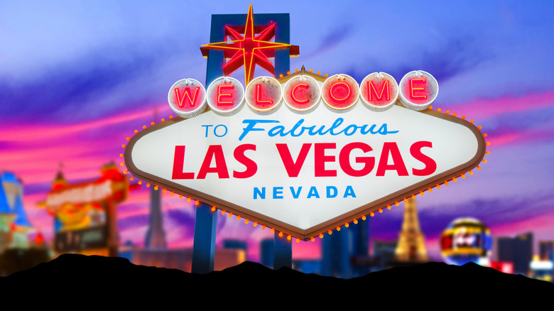 The Las Vegas sign lit at dusk with the strip lit behind it