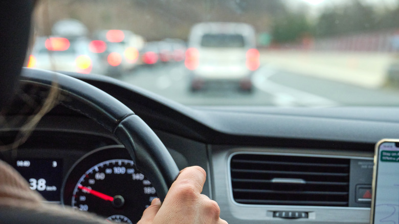 Close-up of a person behind the steering wheel of a car.