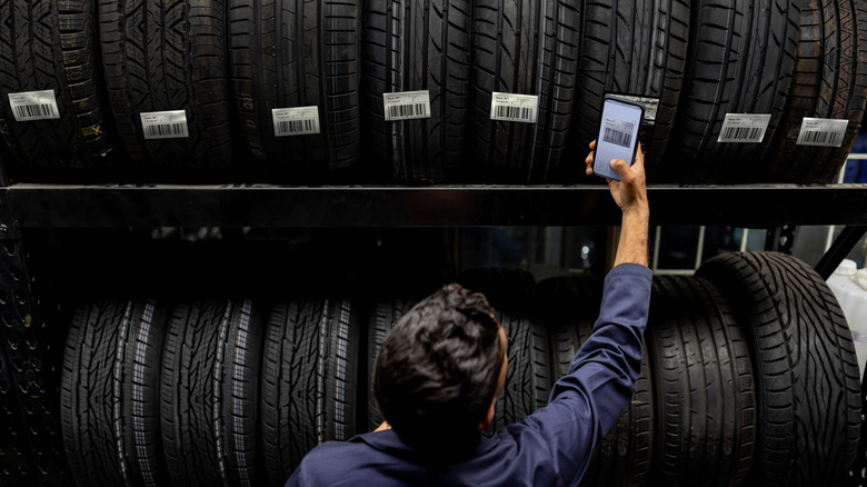 A person scanning a tire on a rack.