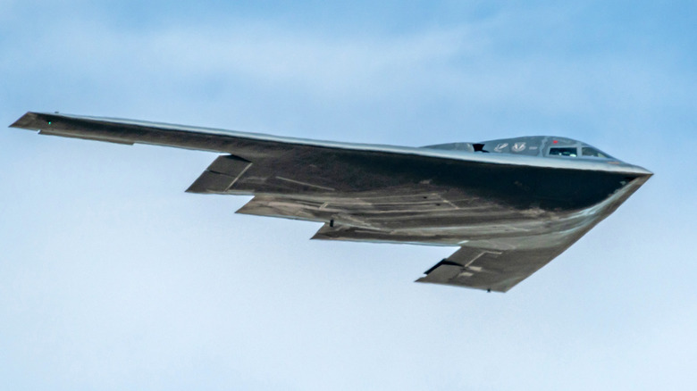 A Northrop B-2 bomber is in flight against a cloudy sky