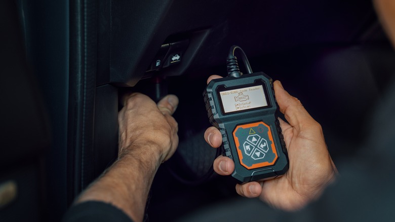 Car technician holding an OBD-II scanner to check for errors