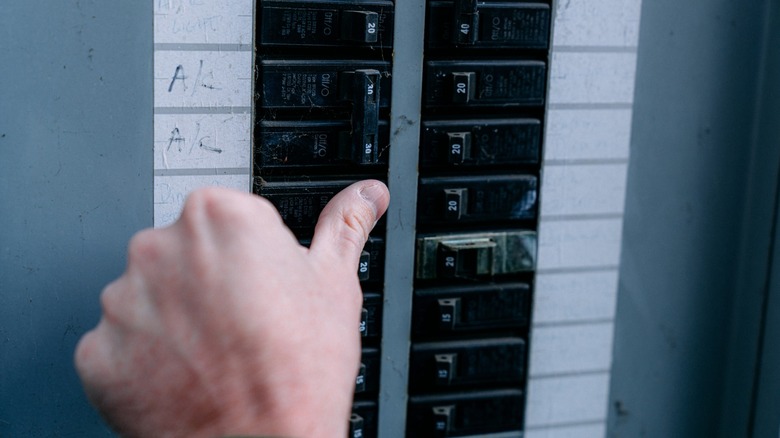 Person's hand adjusting circuit breaker switches