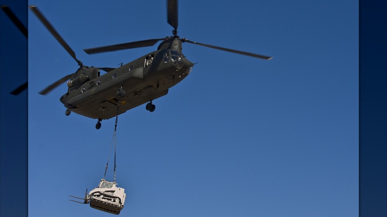A CH-47 Chinook helicopter carries a Caterpillar D9 bulldozer during a training exercise