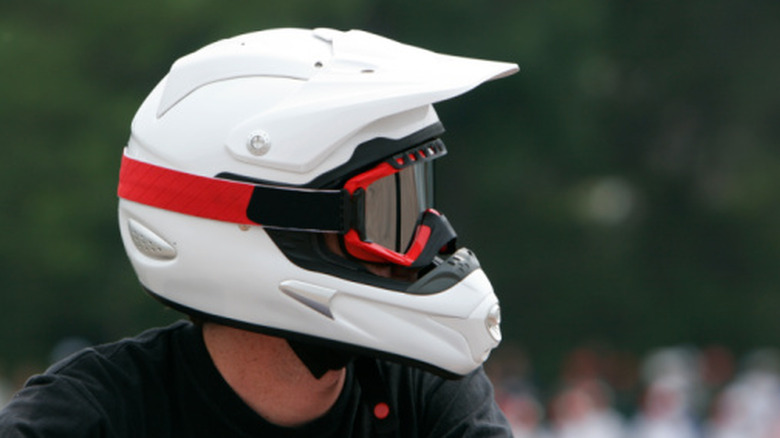 A person in a white racing helmet looking to the right of camera