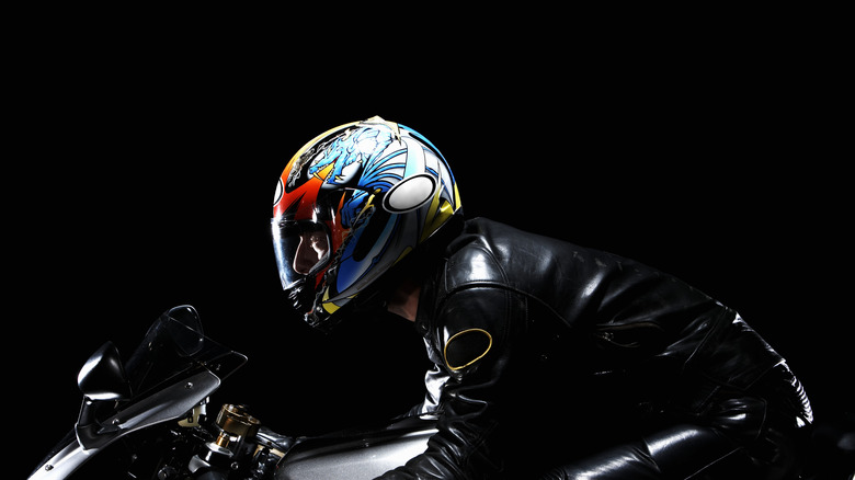 A rider in leather with a colorful helmet mounted on a motorcycle