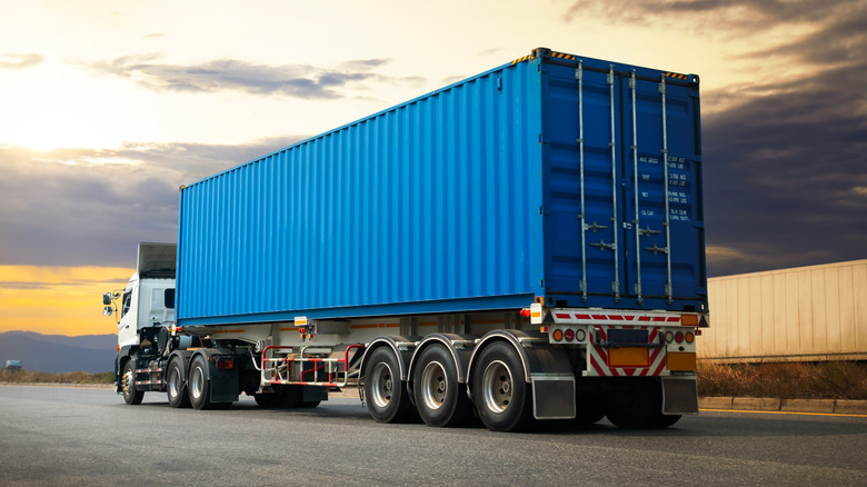 Semi truck with blue trailer sitting in truck parking lot