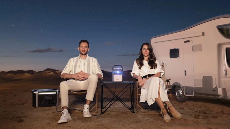 man and woman watching with projector outdoors