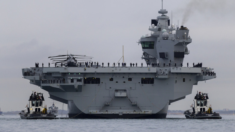 Aircraft carrier with tugs alongside