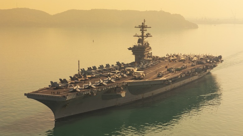 Aerial view of an aircraft carrier against a foggy sea, with jets on the deck