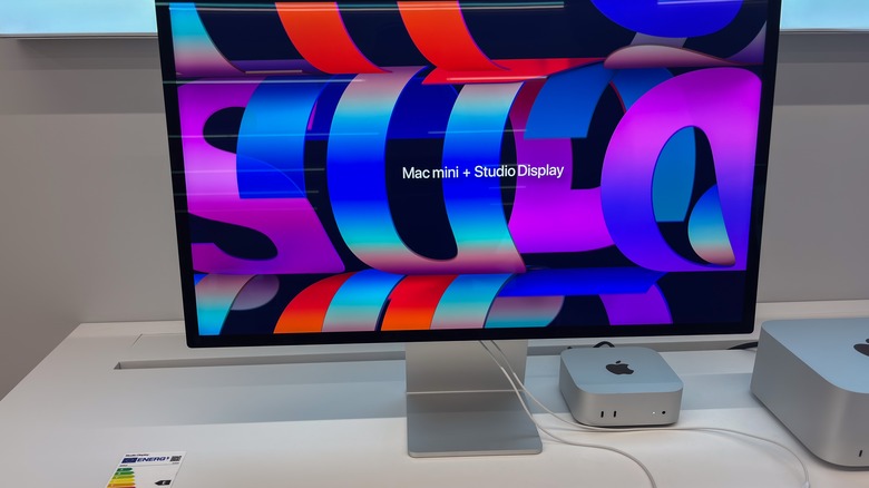 Apple Mac mini and Studio Display set up on a white desk, featuring a vibrant abstract screen background