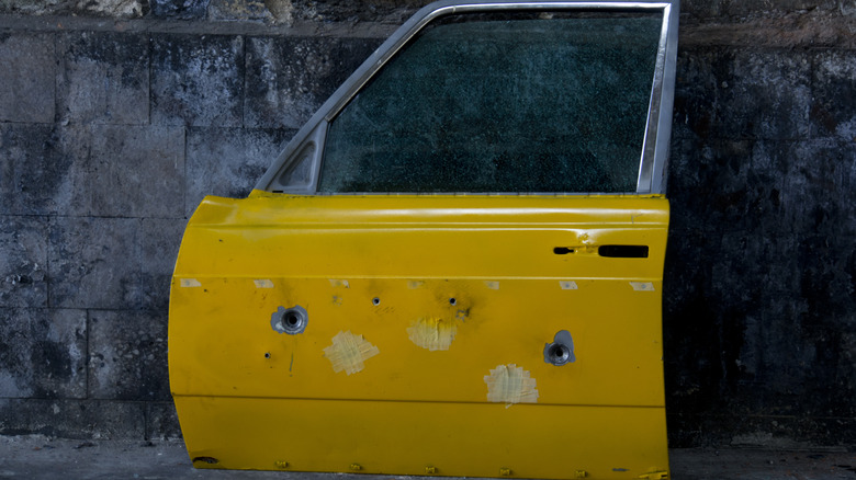 Yellow car door with bullet holes in it