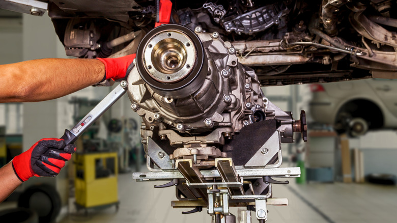 A mechanic working on a vehicle's transmission