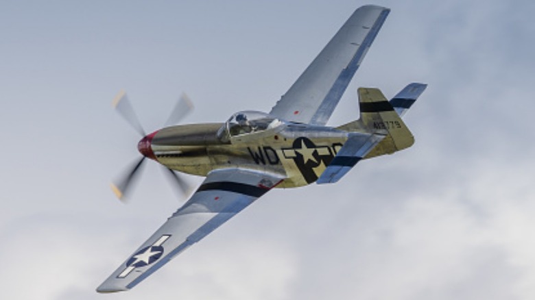 A P-51 Mustang flying over clouds in 2022