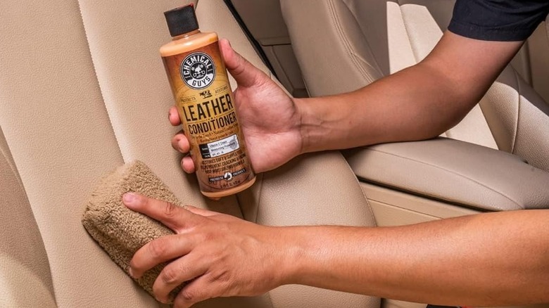 man using leather conditioner on tan car seat