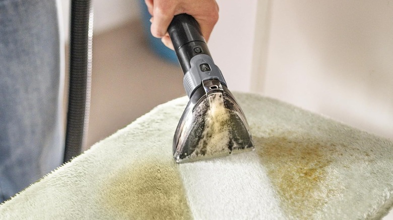 portable upholstery cleaner sucking dirt from green bath mat