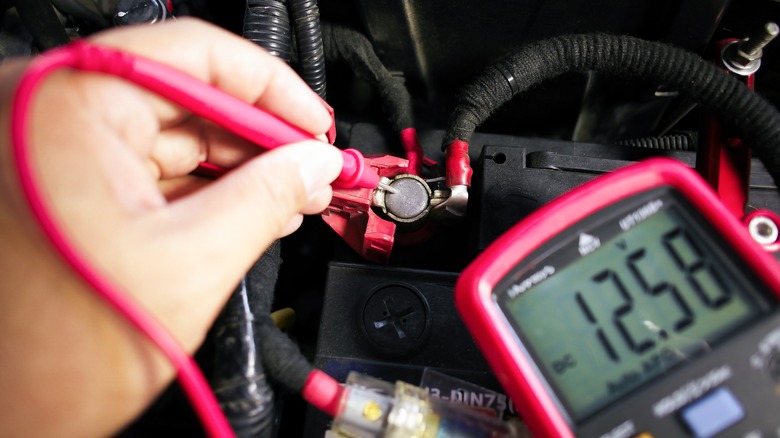 Mechanic using a voltmeter to check the car battery