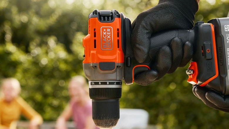 A person using a Black & Decker power drill with a 20V battery.