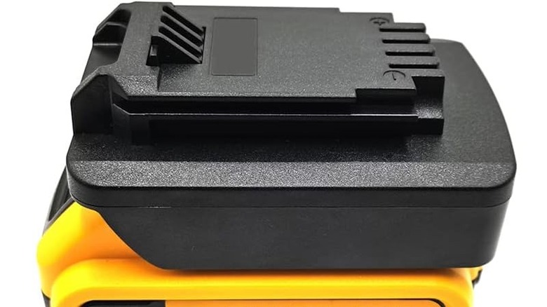 A battery adapter on top of a DeWalt battery pack.