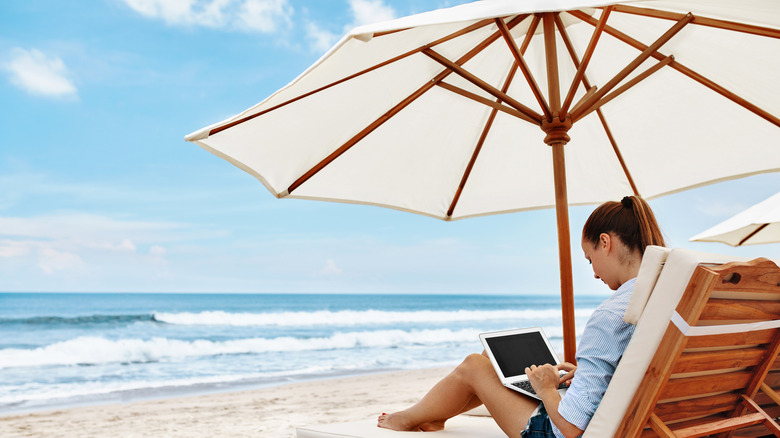 woman using her laptop on a beach